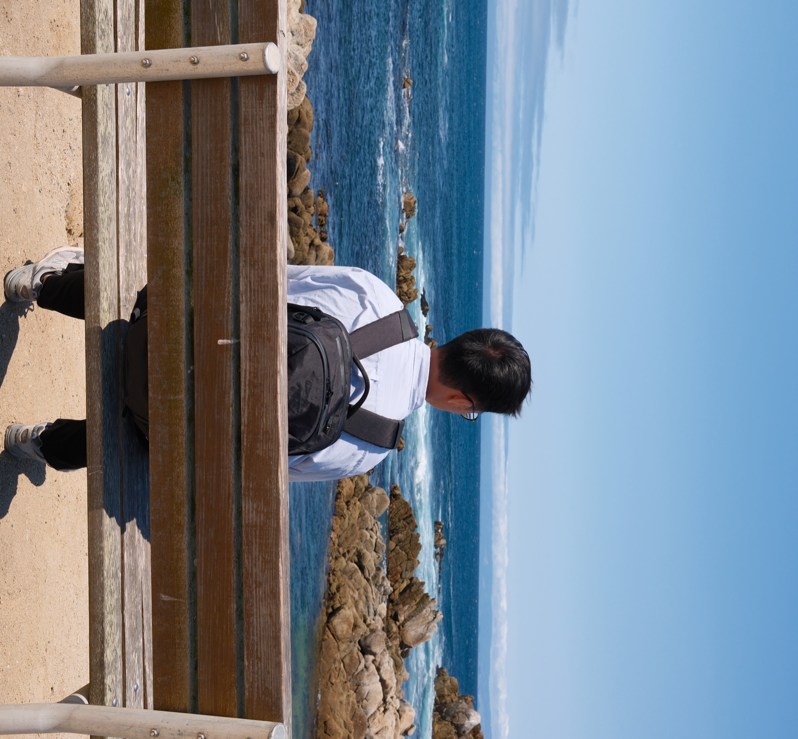 Wei-Hao Lee sitting on a bench overlooking the ocean